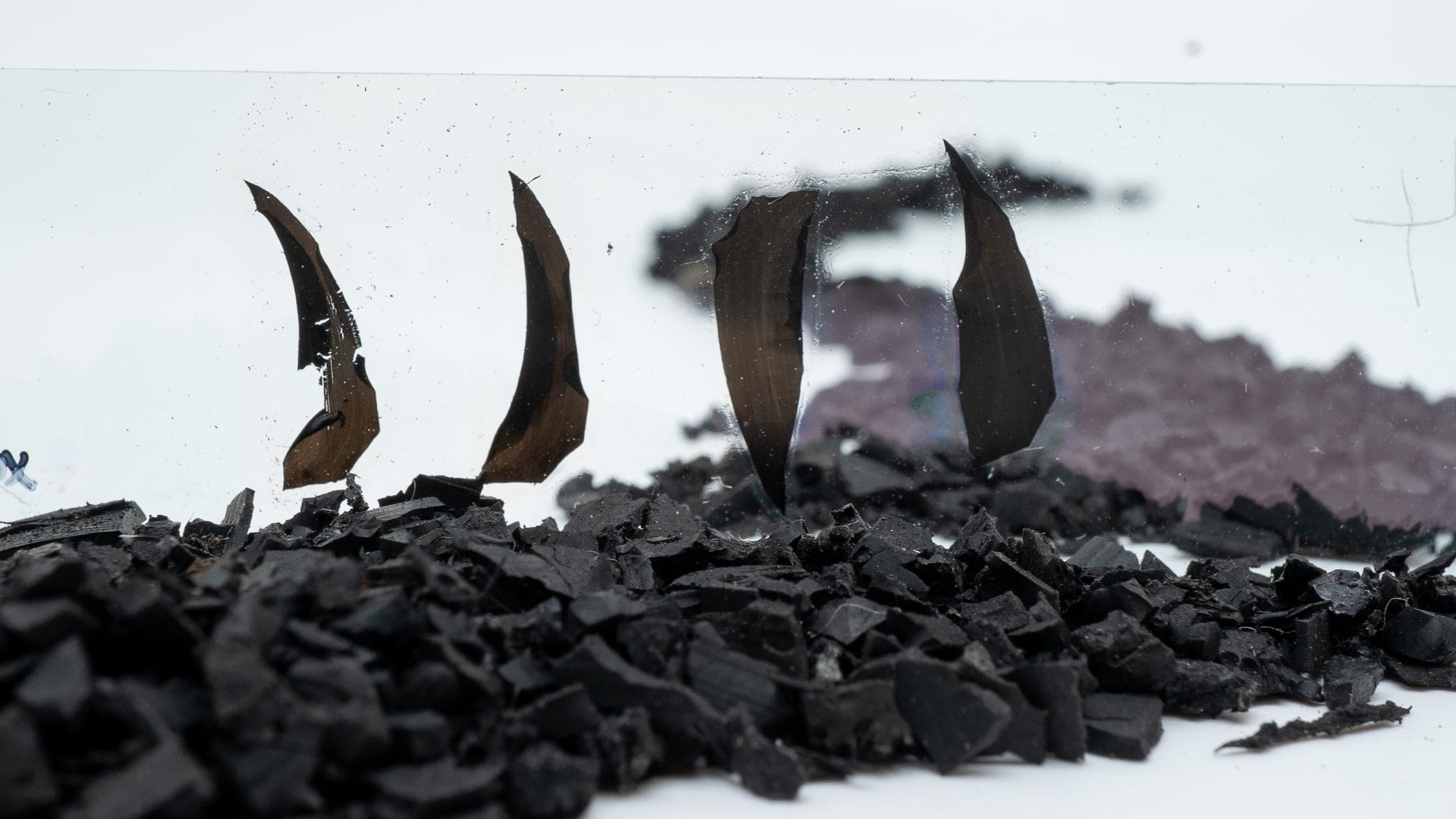 Recovered rubber crumb with thin cut rubber sections standing on a glass pane